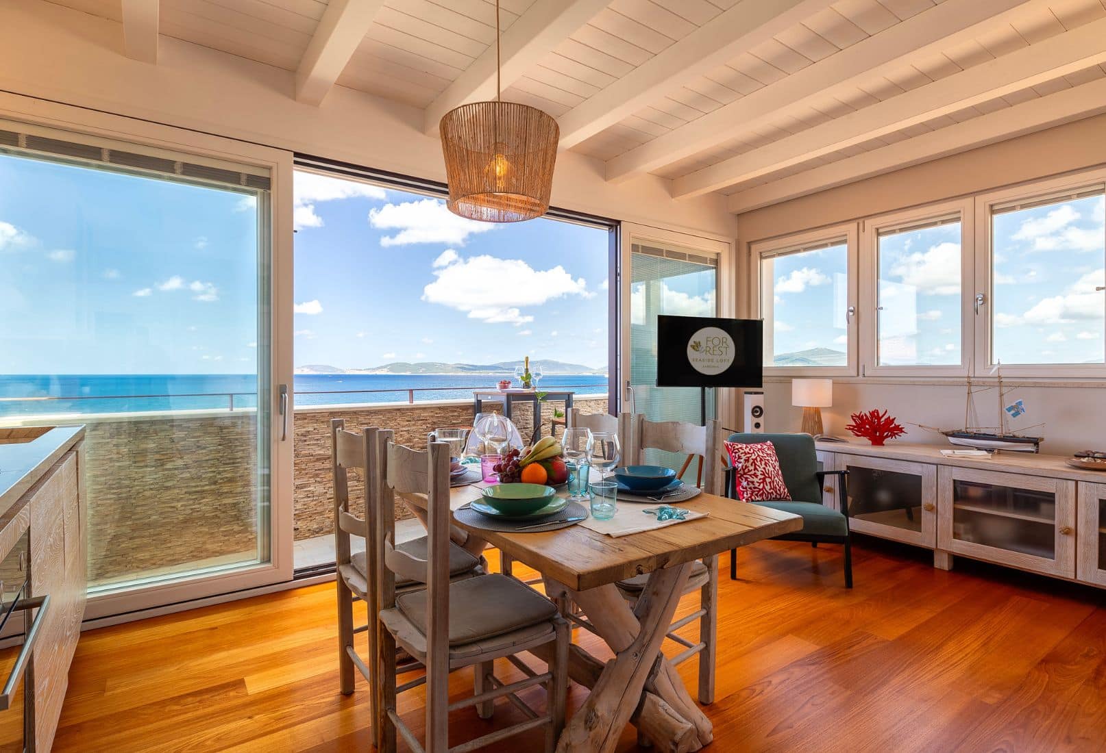 Bright living and dining area with sea view terrace in an Alghero apartment, Sardinia. Zona giorno e pranzo luminosa con terrazza vista mare in appartamento ad Alghero, Sardegna.